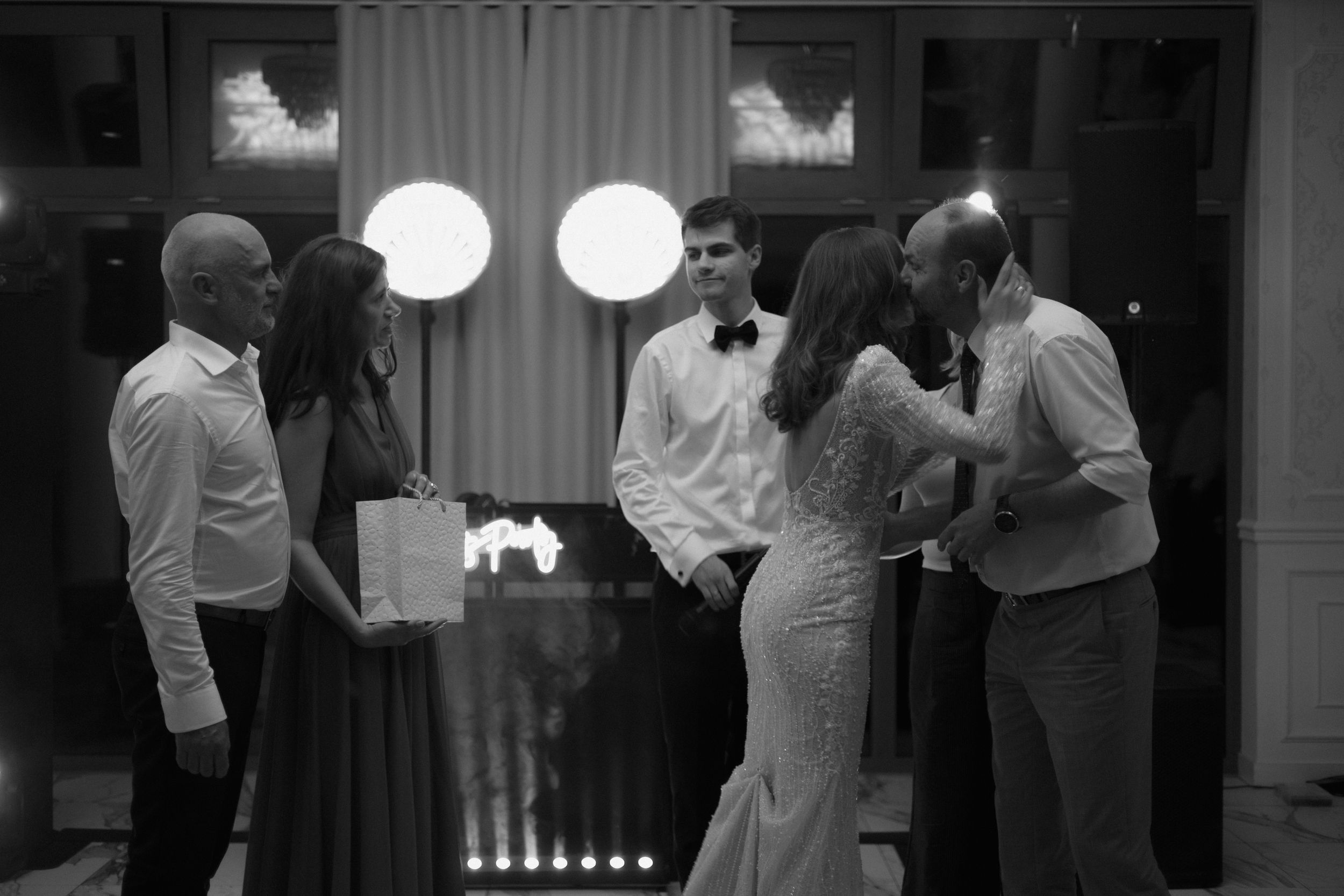 Black and white photo of a small group engaged in conversation at an evening gathering.