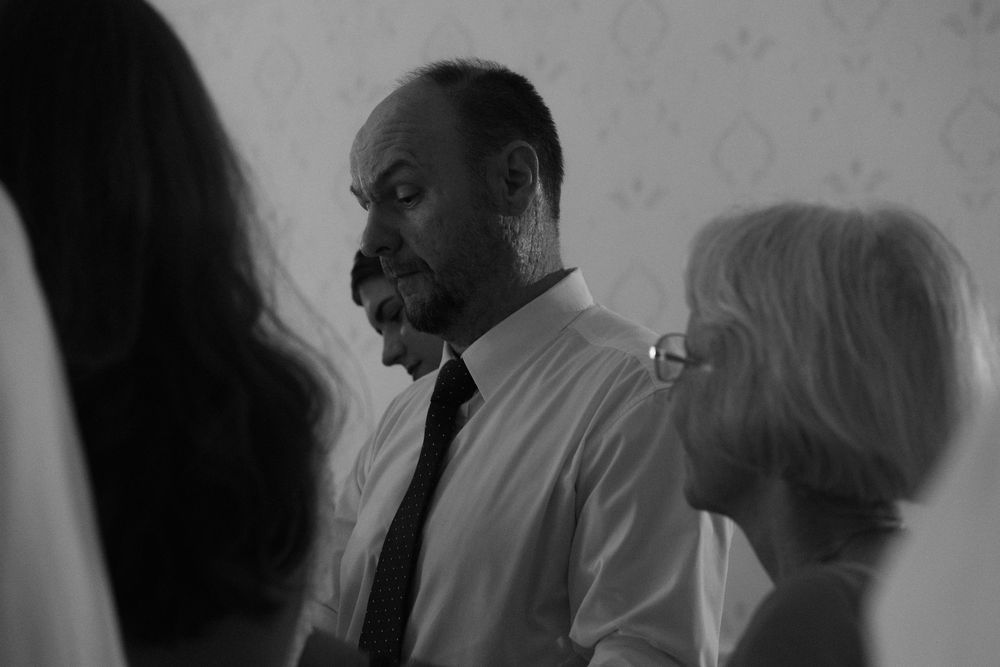 A black and white profile shot showing several people in a group, with one person wearing a white dress shirt and tie.
