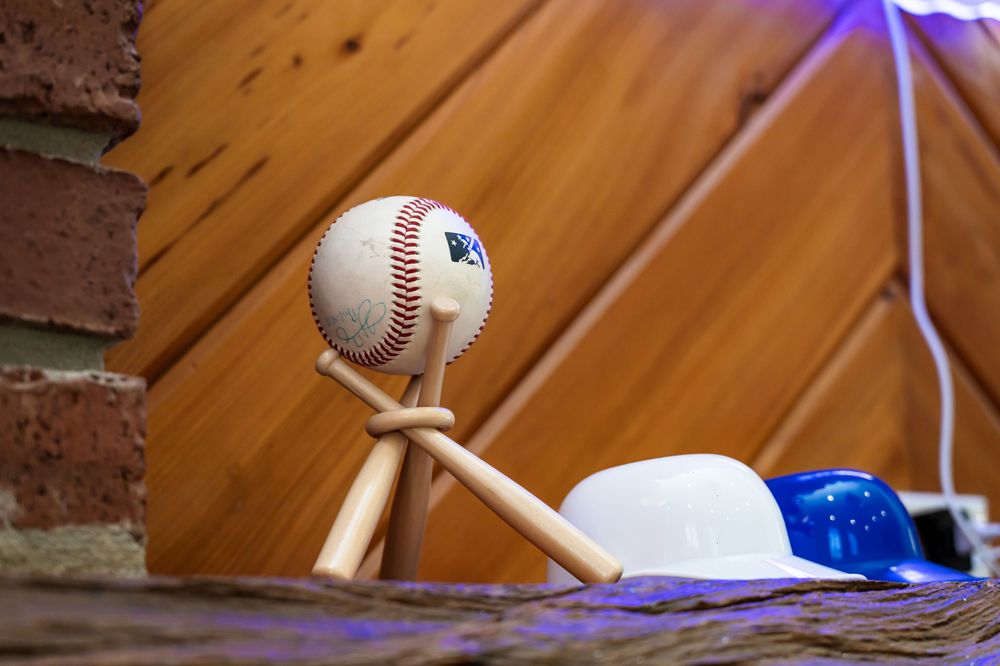 Baseball-themed party setup with blue and red balloons over a brick archway.