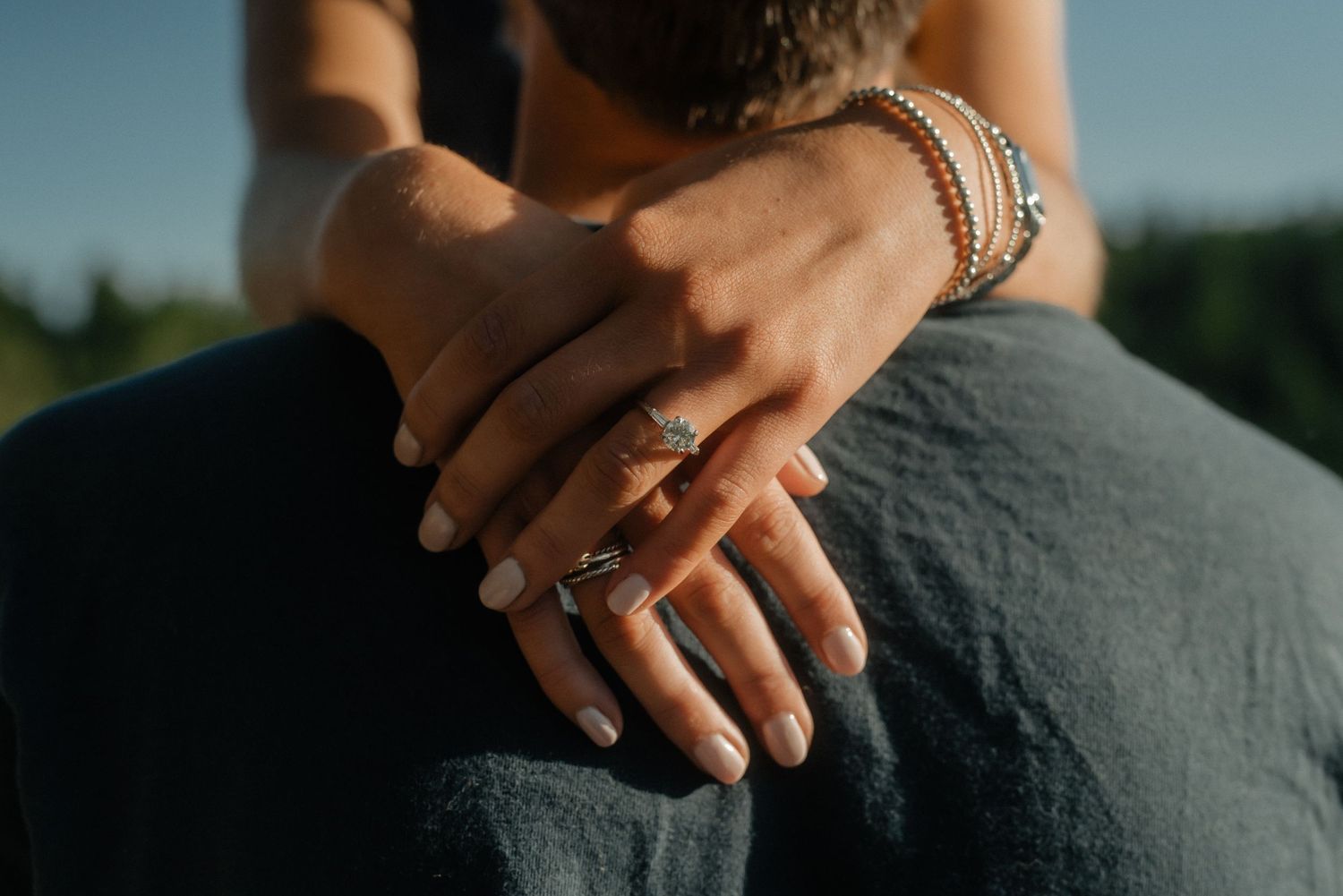 A close-up view of hands resting on a gray fabric surface in soft natural light.
