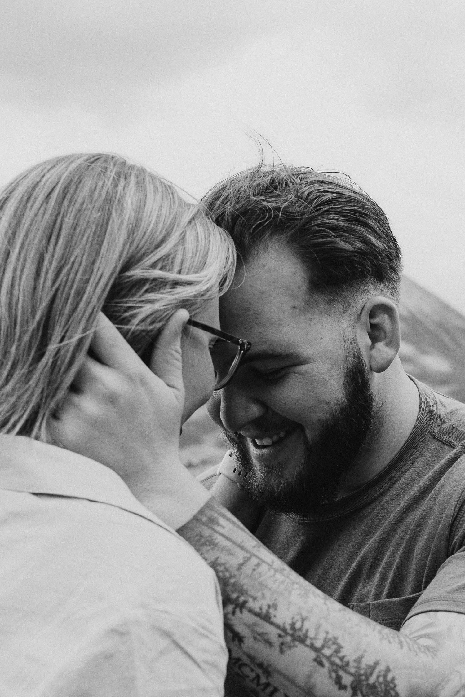 Two people share an intimate black and white moment together against a gray background.