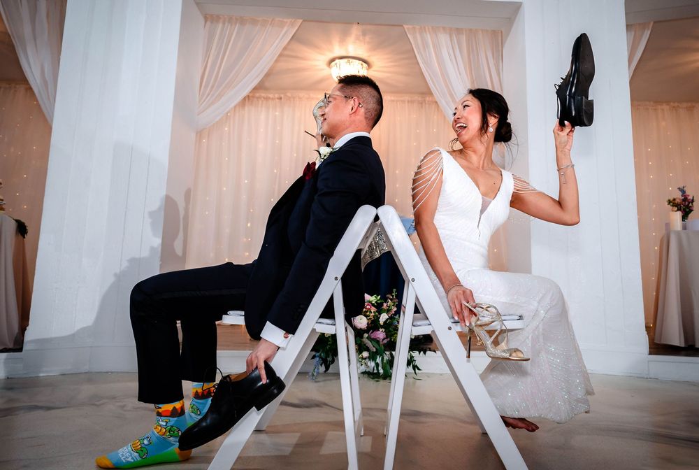 Couple sitting back-to-back on chairs during wedding celebration.