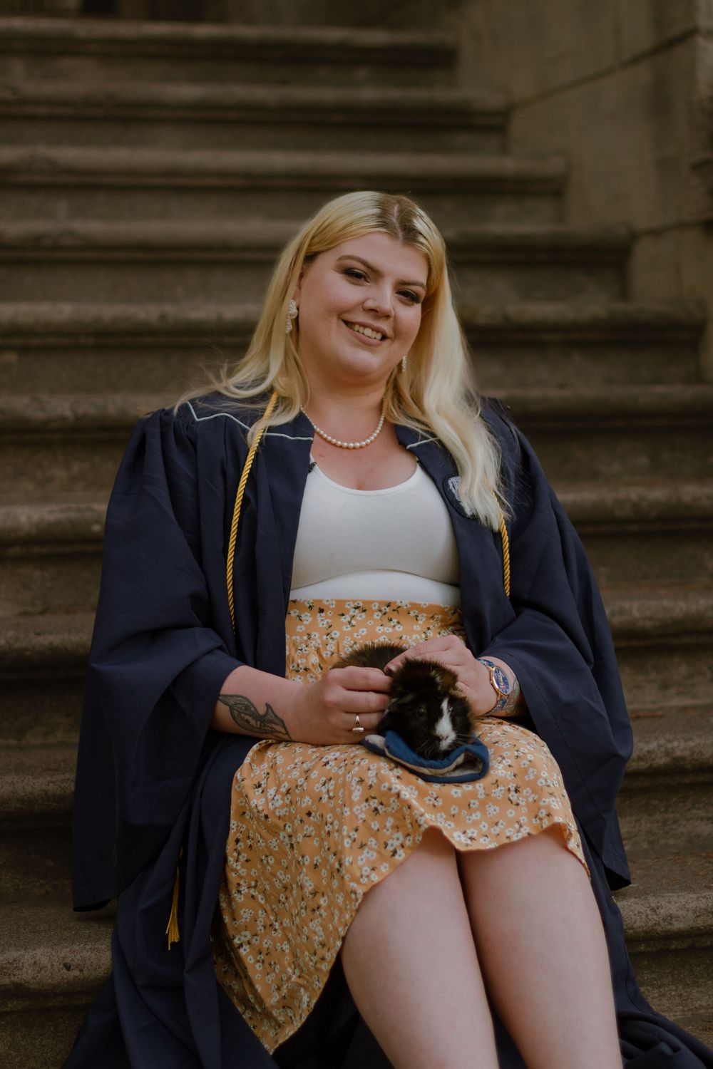 Blonde student sitting on stairs with guinea pig.