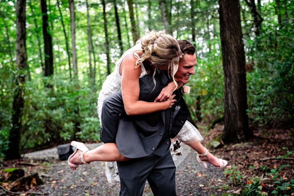 Wedding party enjoys candid moments in a lush forest setting.