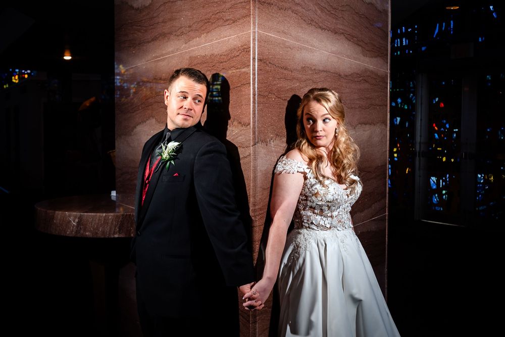 Romantic wedding portraits captured in moody lighting against textured wall.