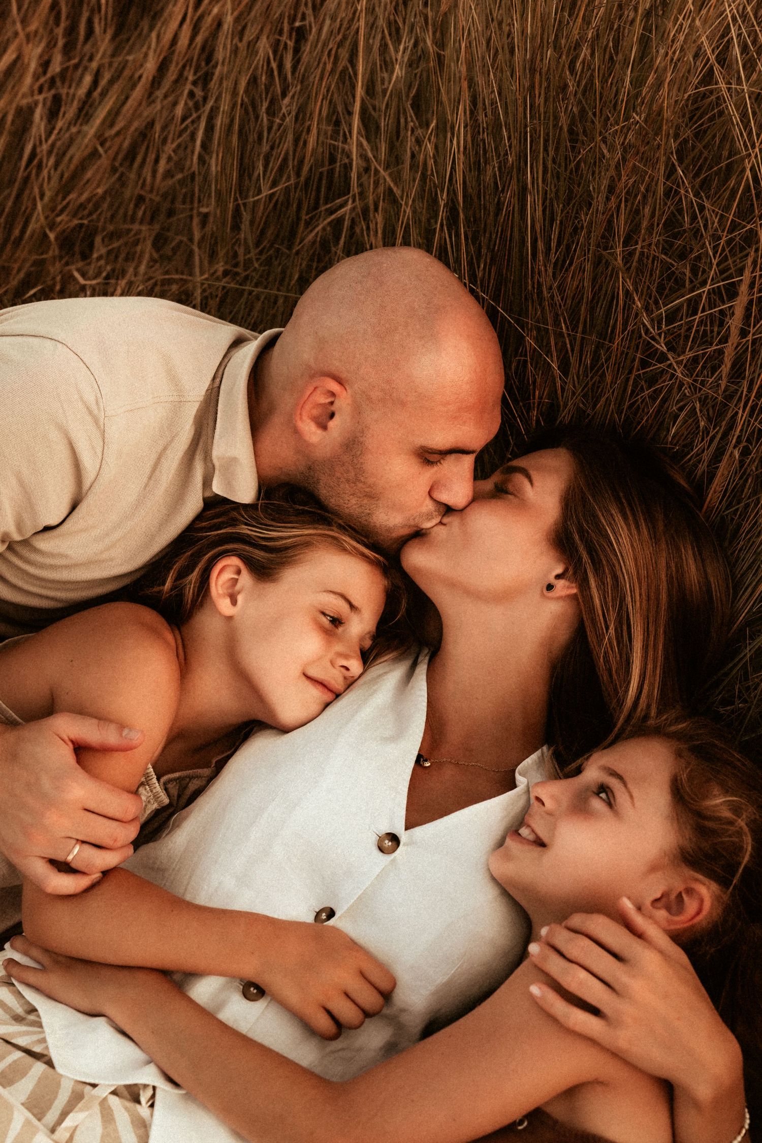 A couple shares intimate tender moments while lying down together in a romantic photo sequence with their children. Javea photographer
