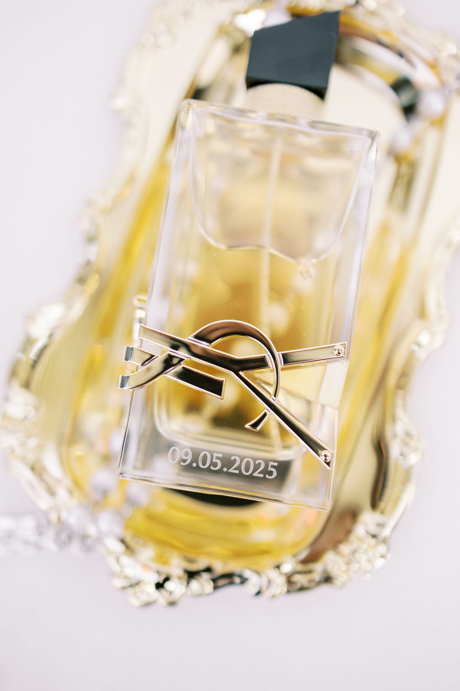 Three crystal perfume bottles with a yellow fragrance liquid and silver cap designs photographed up close.