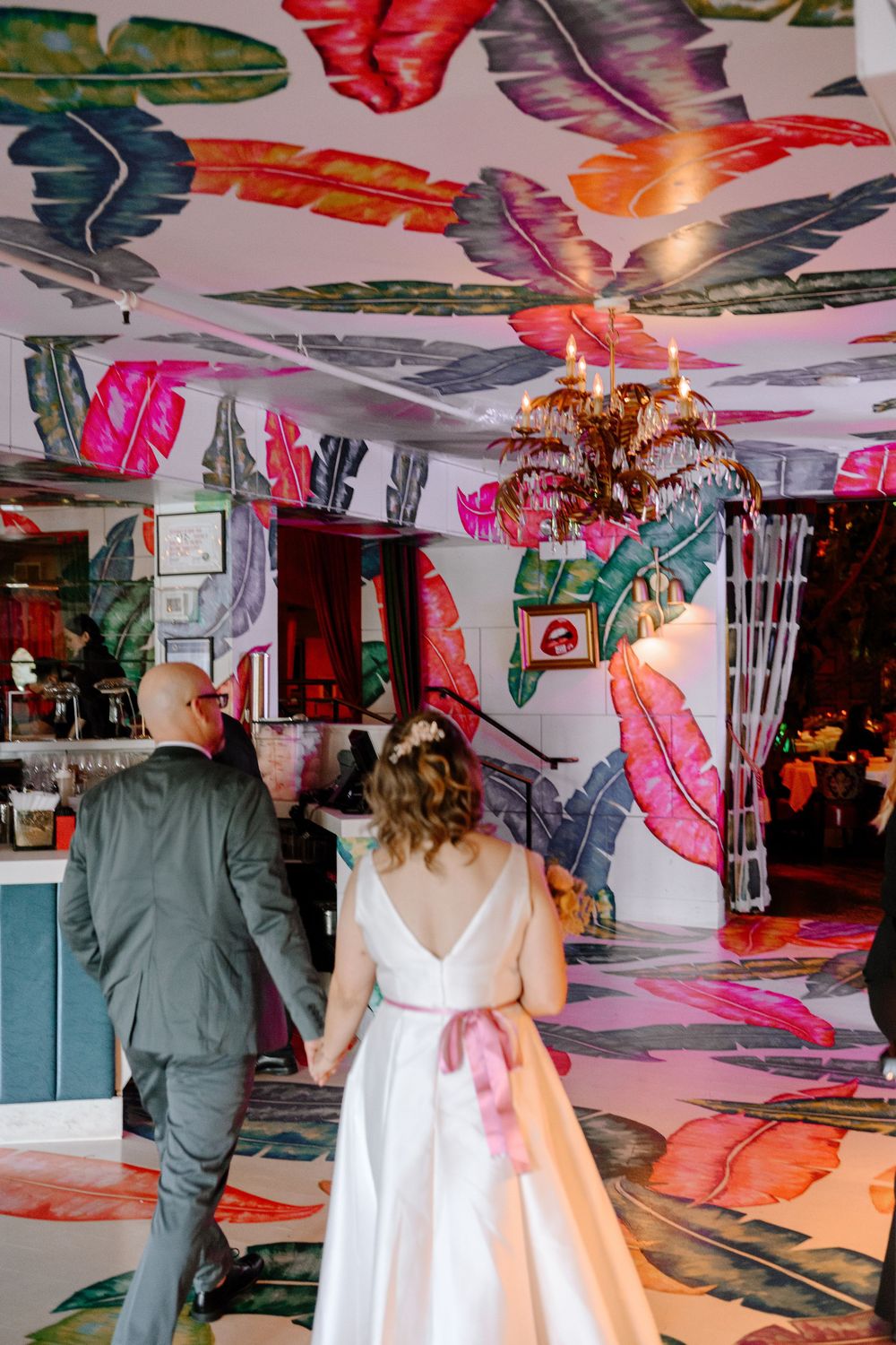 Wedding venue space decorated with vibrant pink and green leaf projections on white walls and ceiling.