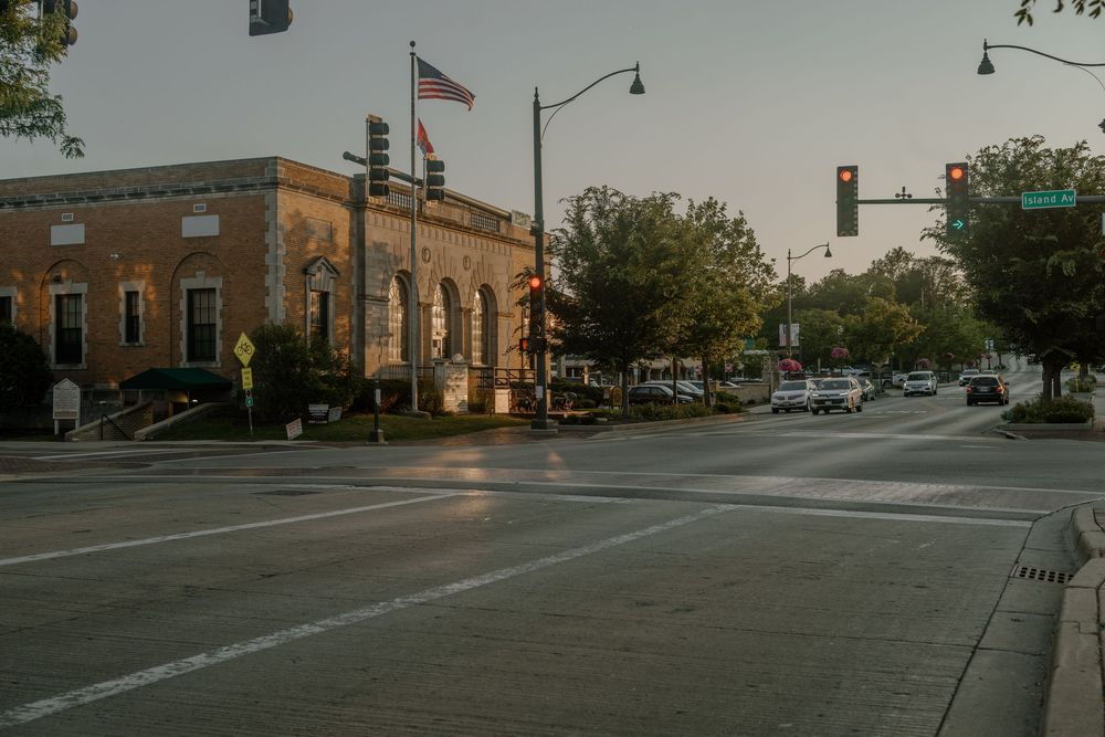 A panoramic view of a small town street corner with brick buildings and traffic signals during daytime.