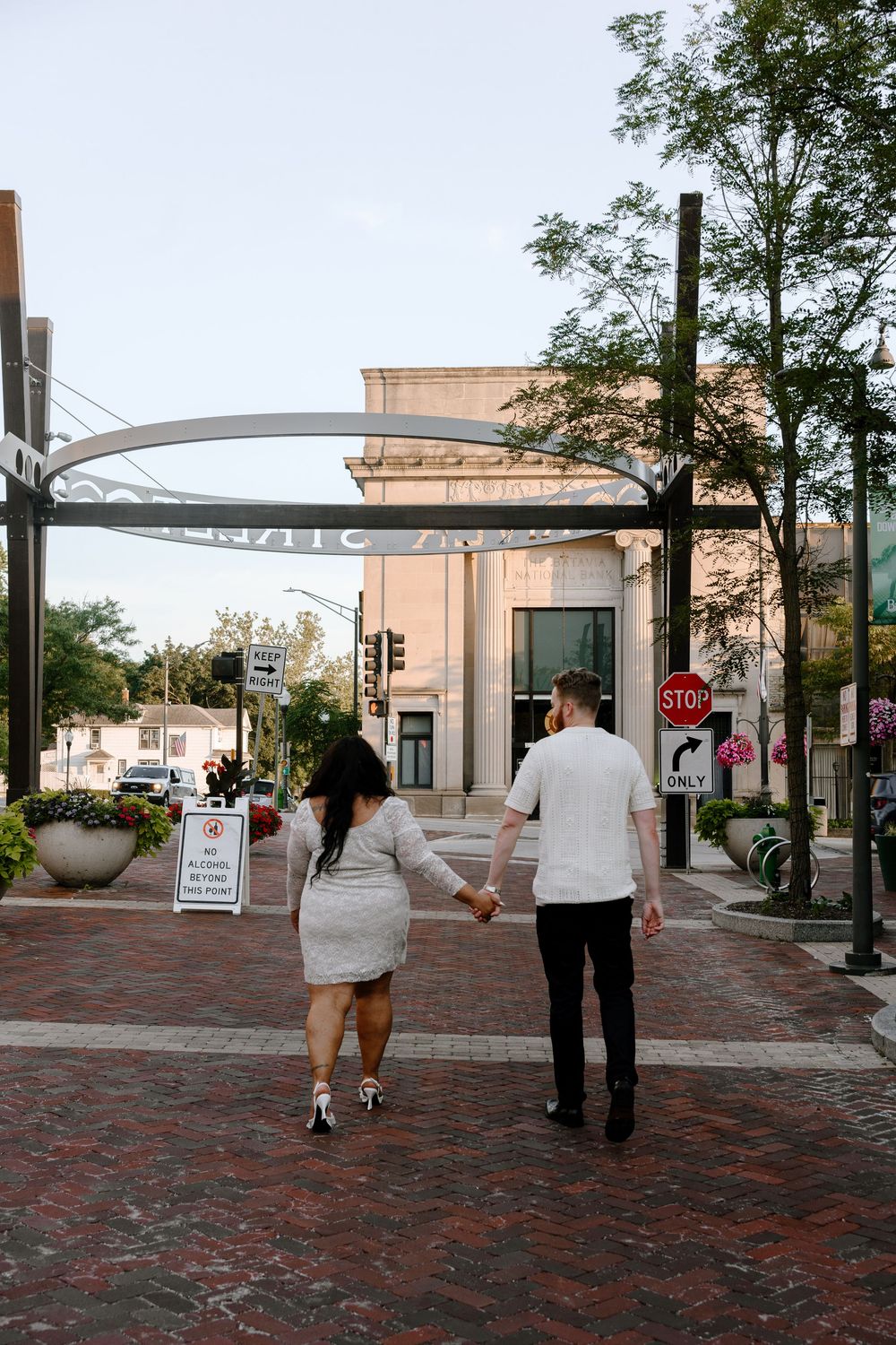 A couple walking together on a brick paved walkway through an urban plaza.