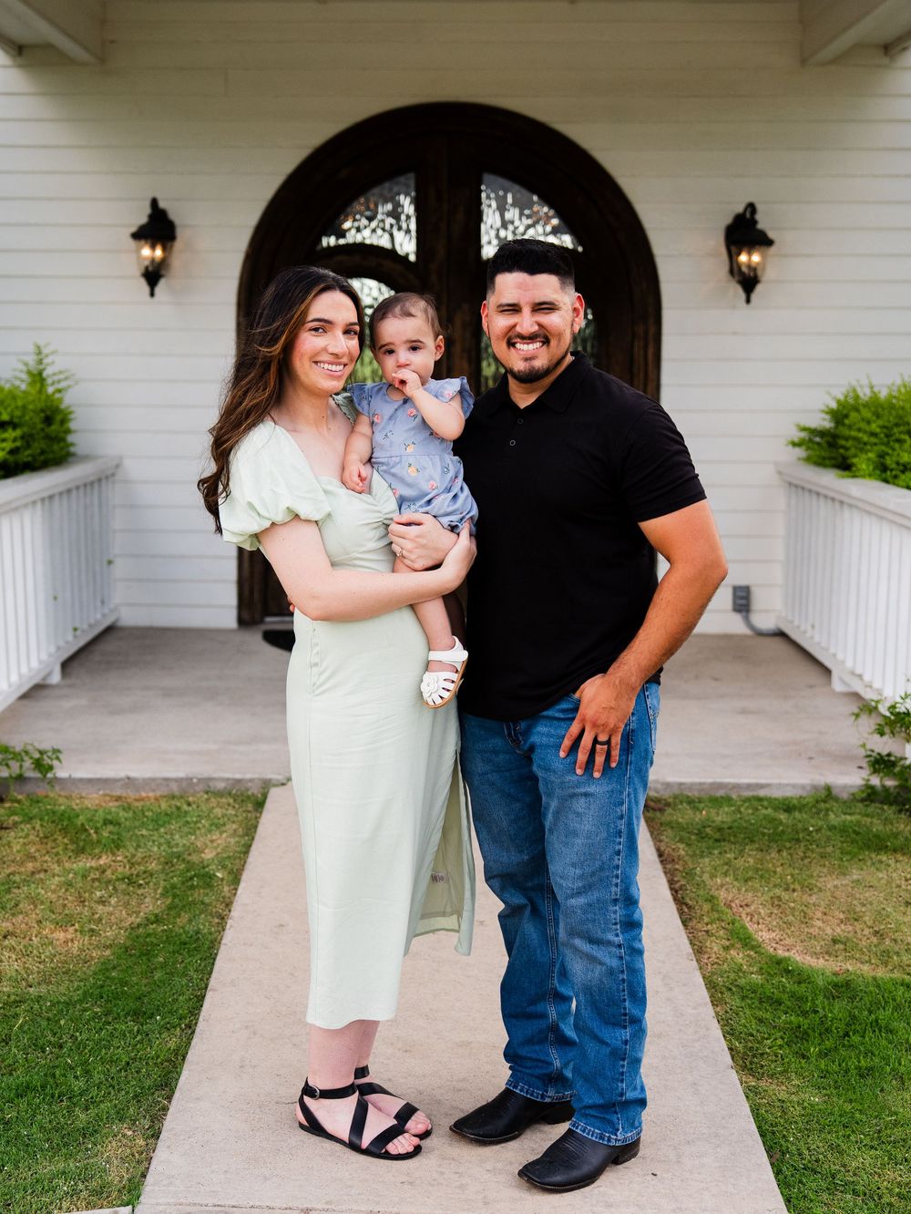 A family group poses together wearing casual attire on a porch with white columns.