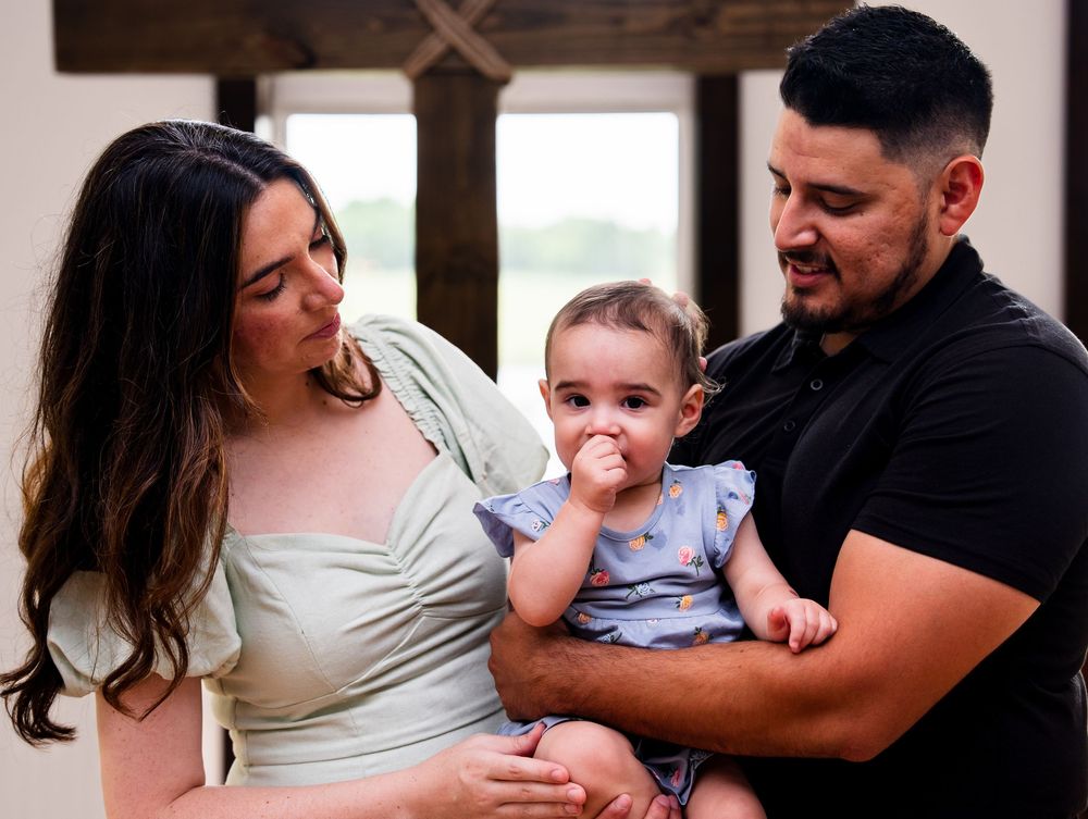 Sweet family photography session showing candid moments between parents and baby at home in natural lighting.
