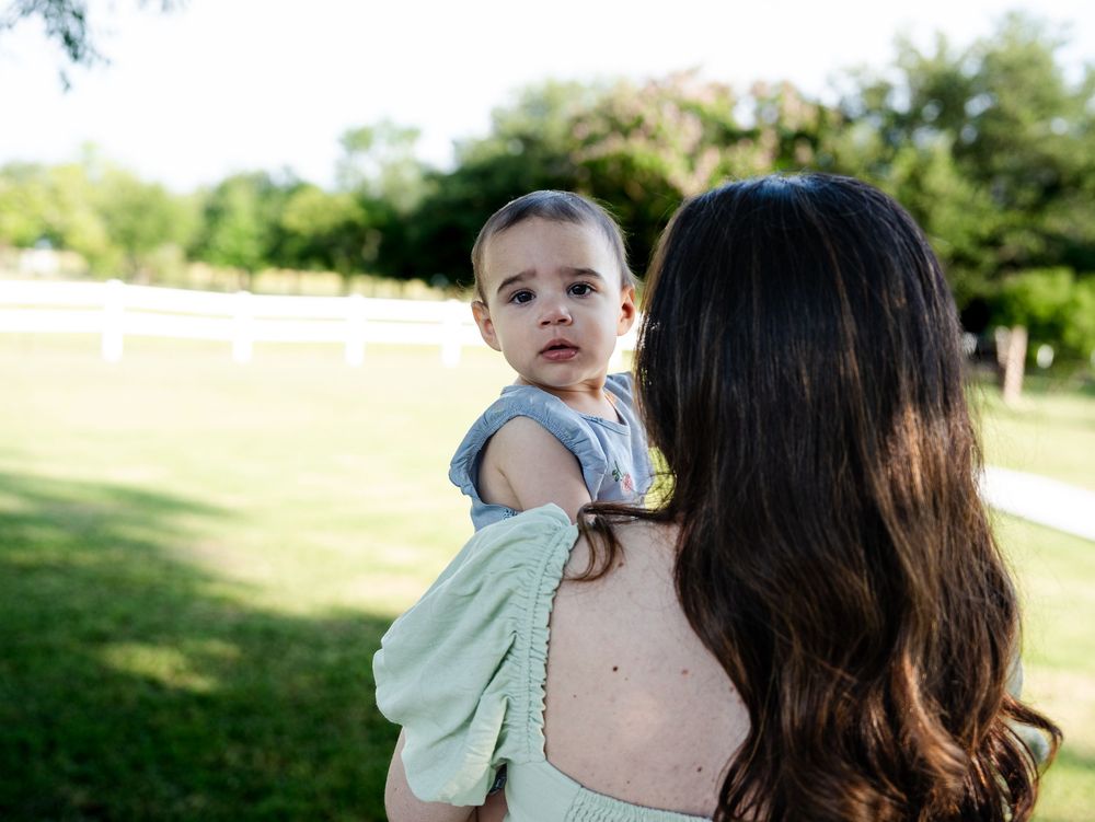 A candid moment captured during a summer photoshoot with people walking in a grassy outdoor park setting.