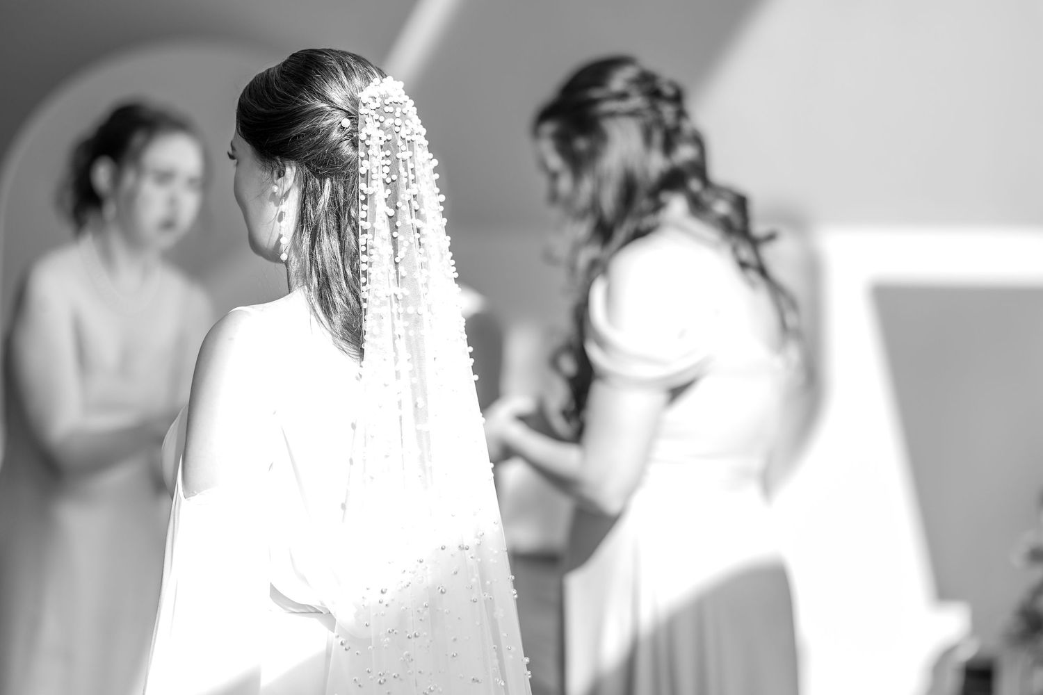 Bride and bridesmaid share a tender moment while getting ready for a wedding ceremony.