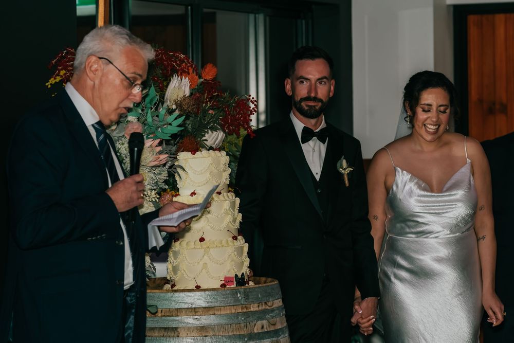 A wedding reception decorated with floral arrangements and wine barrels features guests mingling in formal attire.