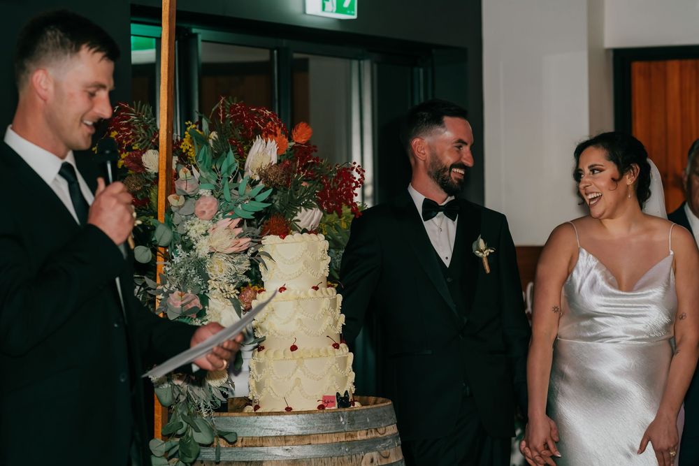 Wedding couple slices into their elegant three-tiered white cake during their reception celebration.