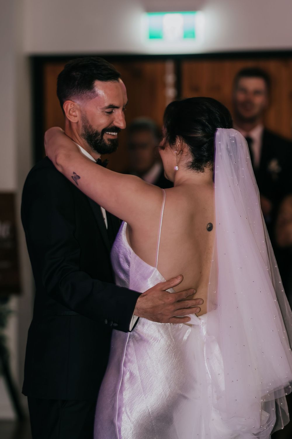 A bride and groom share an intimate first dance at their wedding reception under soft lighting.