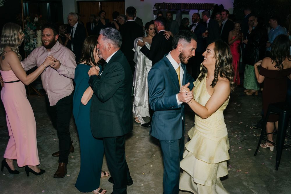 Couples dancing together at an elegant evening reception with dim lighting and formal attire.