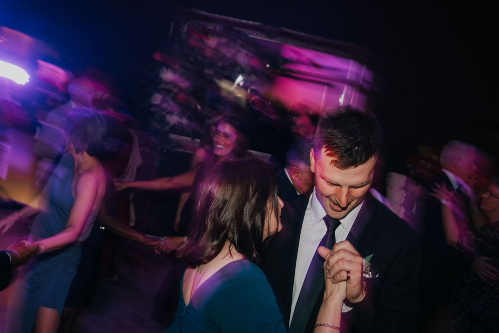 Dancers enjoying a nightclub atmosphere under purple lighting on a crowded dance floor.