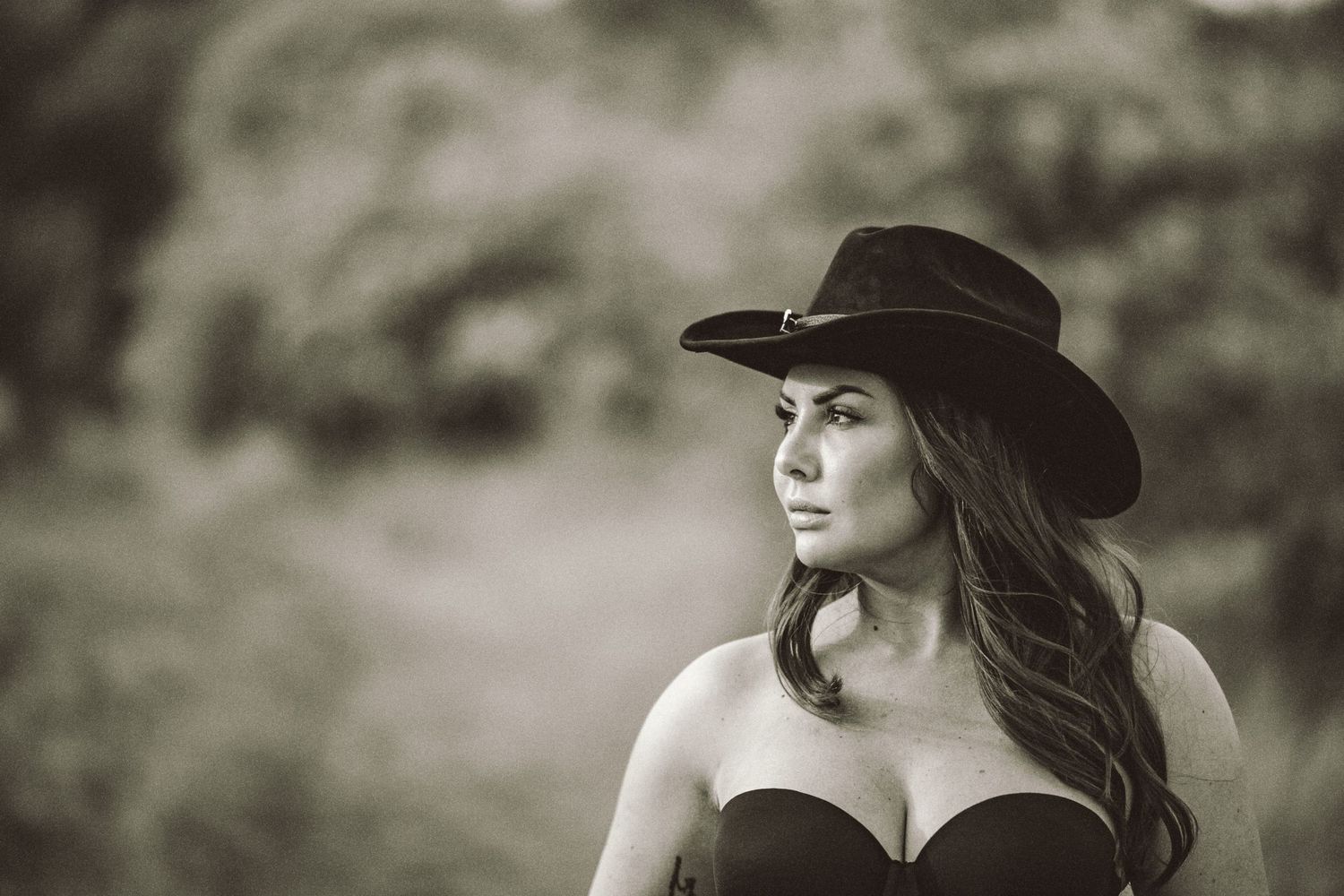 Cowgirl porträtt i svartvitt – kvinna i cowboyhatt och bustier med intensiv blick | Porträttfotograf Malmö