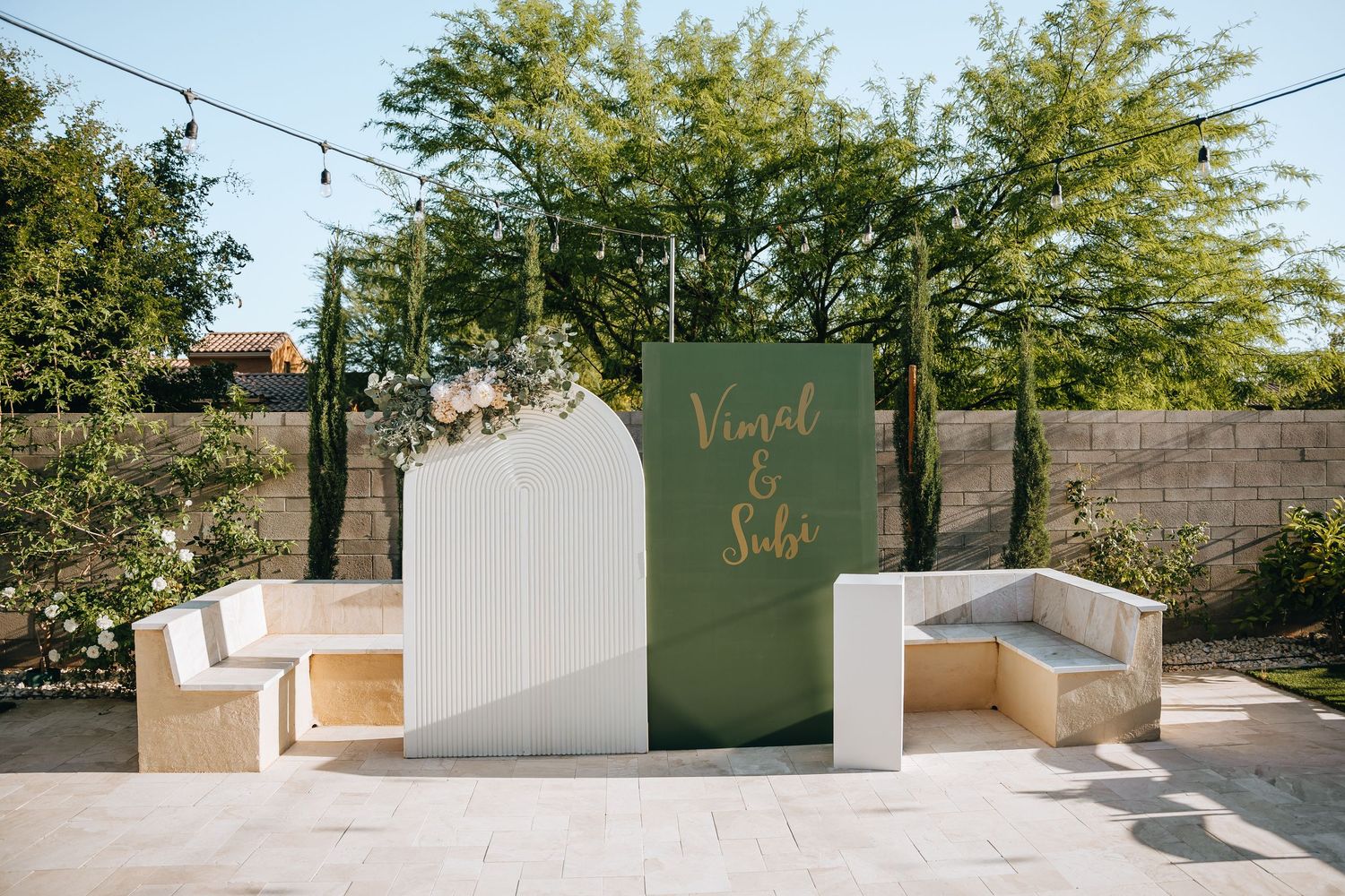Modern outdoor wedding venue with white walls and string lights at sunset.