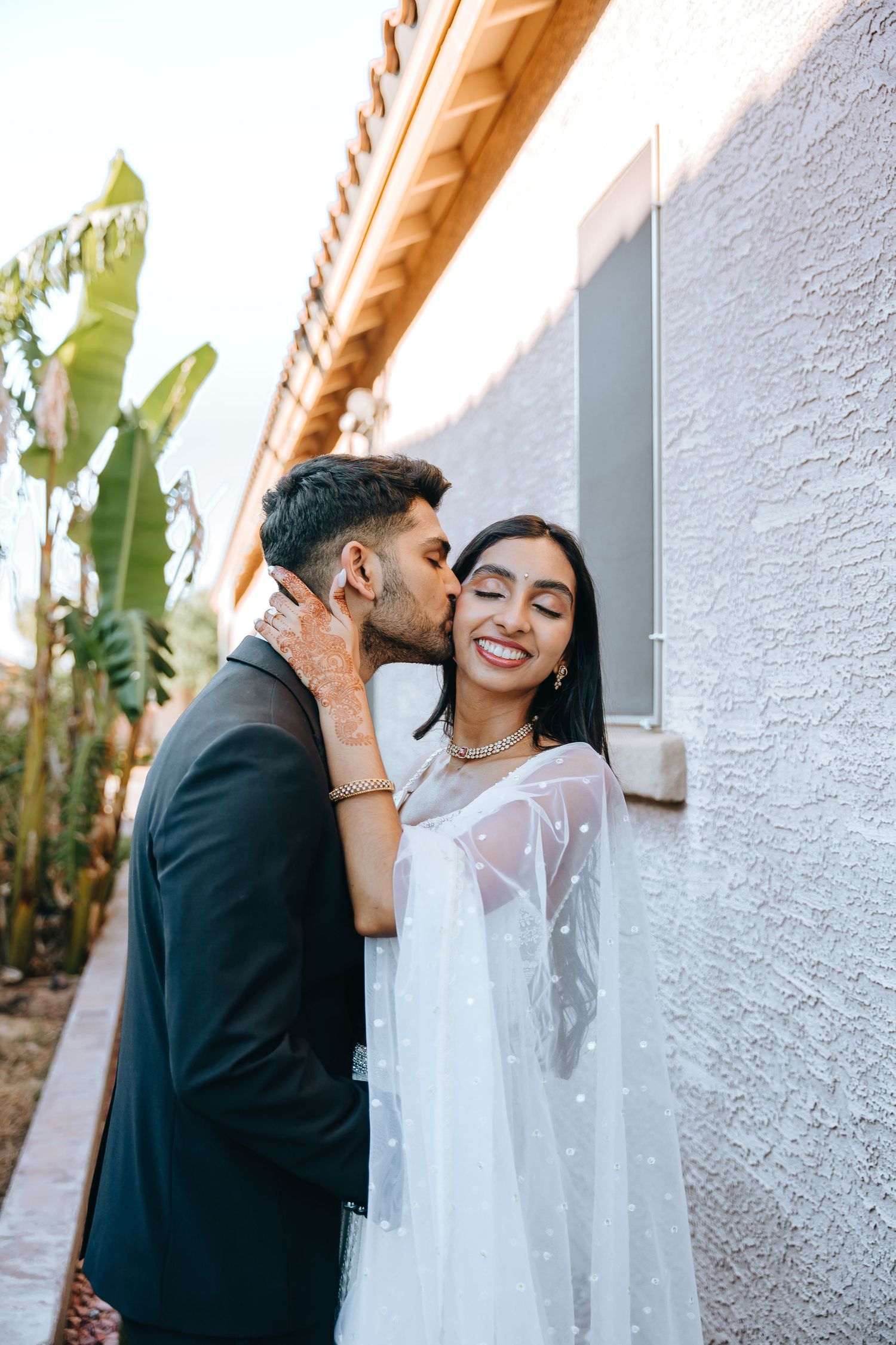 Romantic moment between couple in formal attire against textured wall.