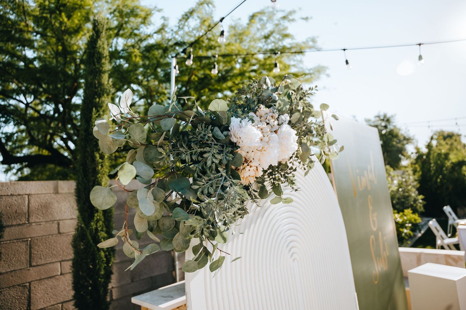 Elegant wedding decor with floral arrangements and string lights in outdoor setting.