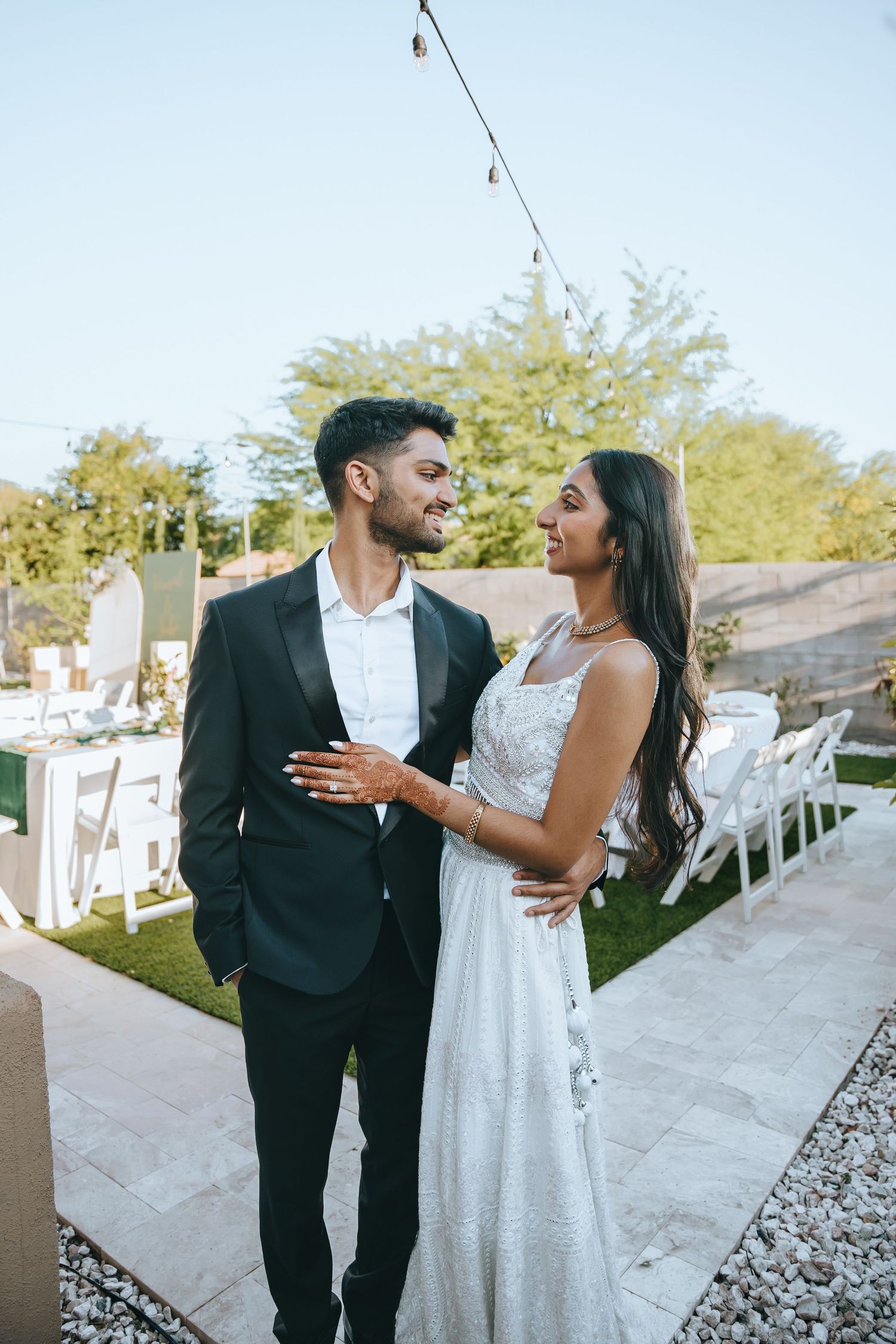 Couple shares laughter during wedding celebration in outdoor venue.