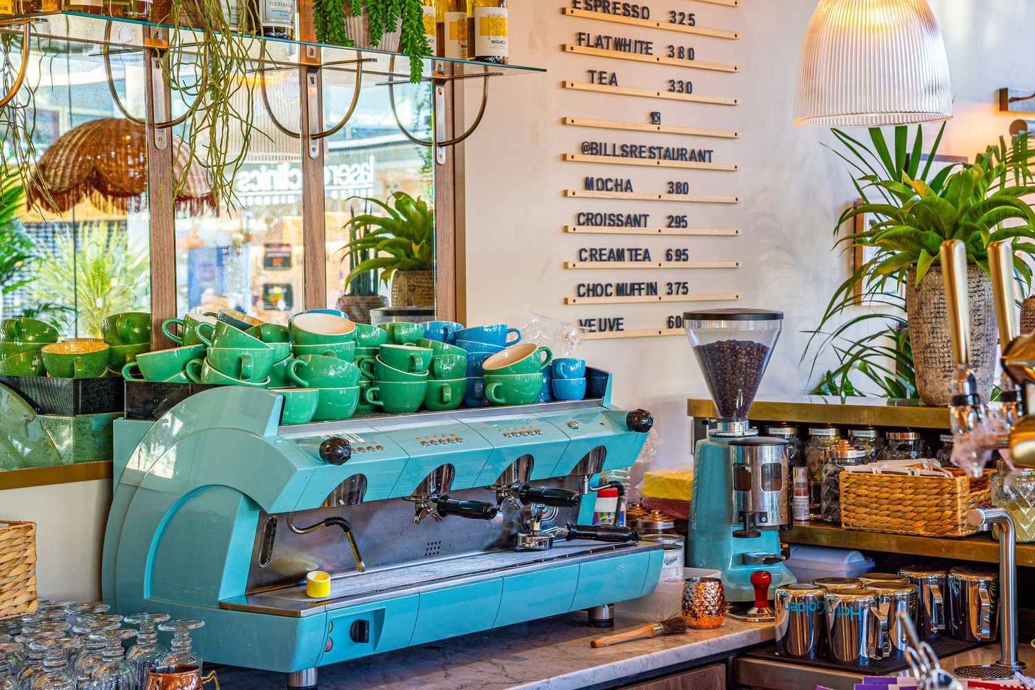 Retro diner interior with turquoise booth seating, orange pillows, and vintage decor in warm lighting.