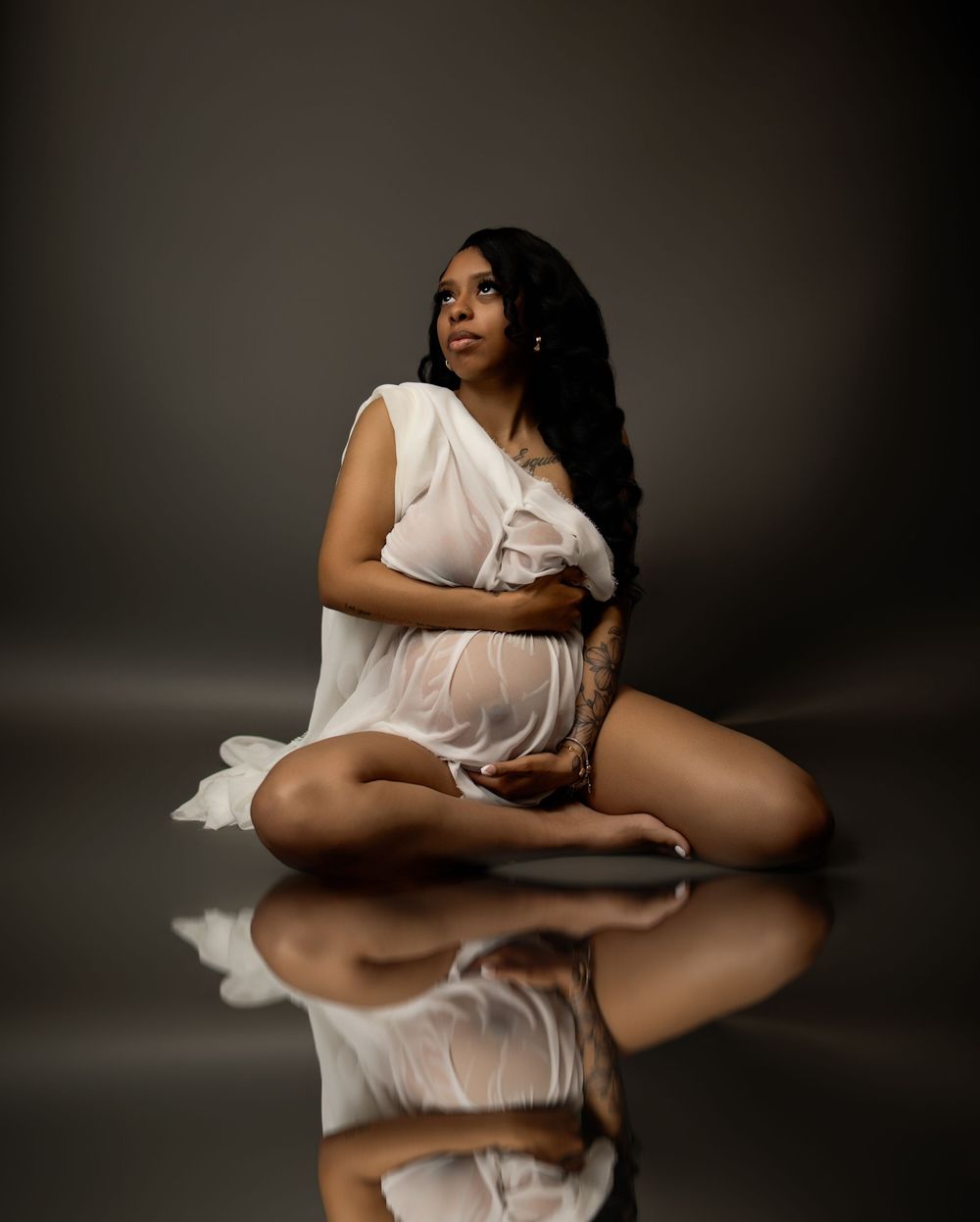 Artistic black and white photo series showing a figure in flowing white fabric creating reflective compositions on dark floor.