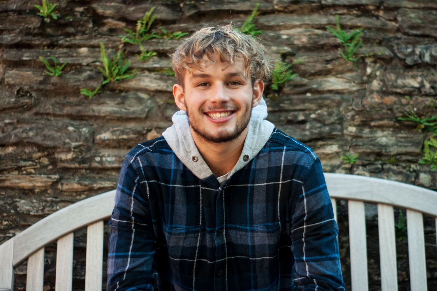 Senior sitting on park bench smiling with stone backdrop at Jeffrey Mansion in Bexley, Ohio by Jamie Macey Photography