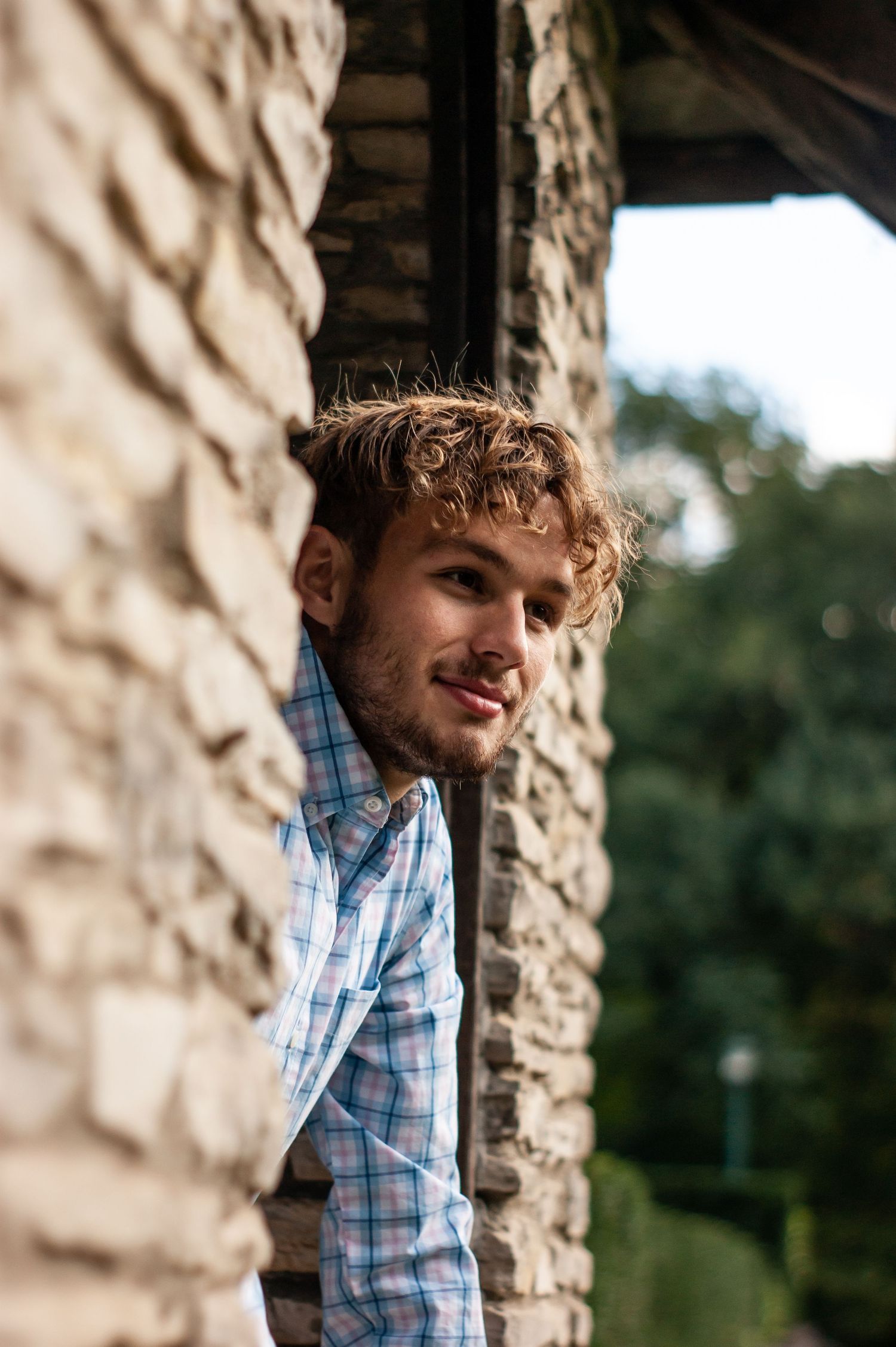 High school senior leaning against a stone wall during an outdoor portrait session, by Jamie Macey Photography, in Columbus, Ohio.