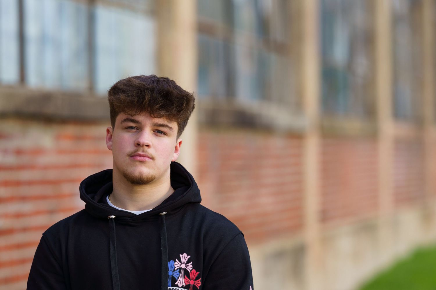 High school senior standing in front of a brick building during an outdoor portrait session, by Jamie Macey Photography, in Columbus, Ohio