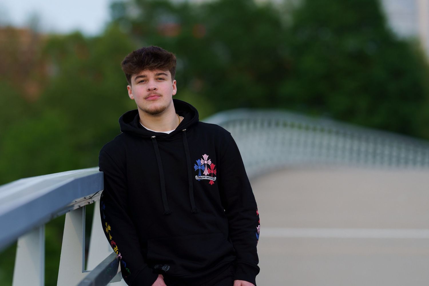 High school senior in a black hoodie posing on a pedestrian bridge, by Jamie Macey Photography, in downtown Columbus, Ohio.