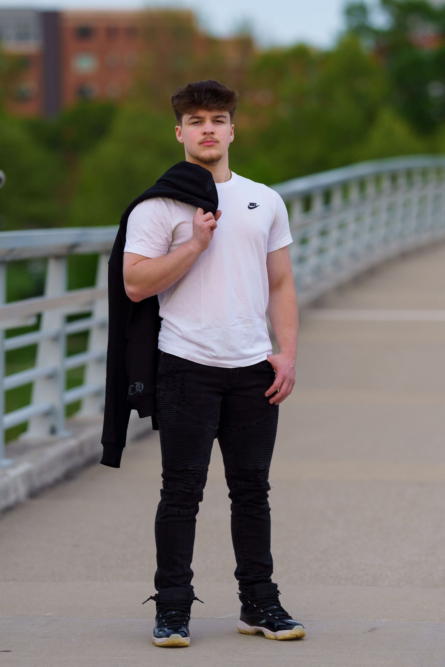 High school senior standing near a bridge railing during a downtown portrait session, by Jamie Macey Photography, in Columbus, Ohio.