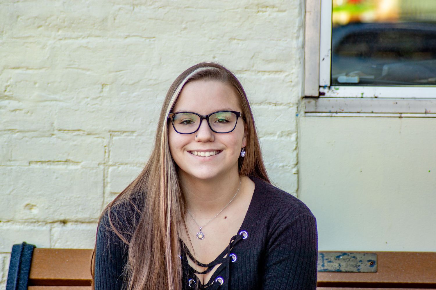Smiling high school senior sitting outdoors during a portrait session, by Jamie Macey Photography, in Columbus, Ohio.