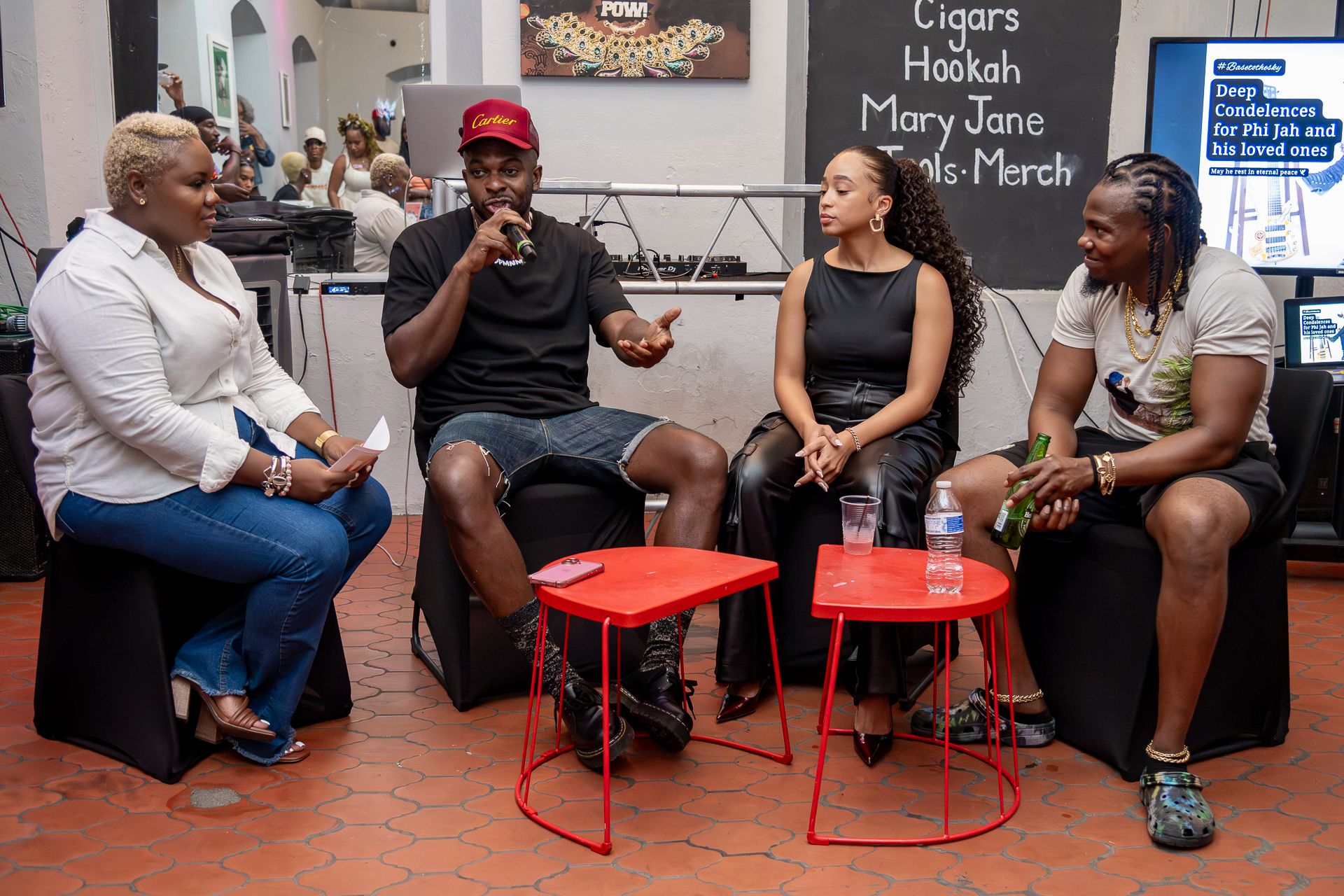 People gathered in conversation on colorful chairs during a social event at an urban setting.