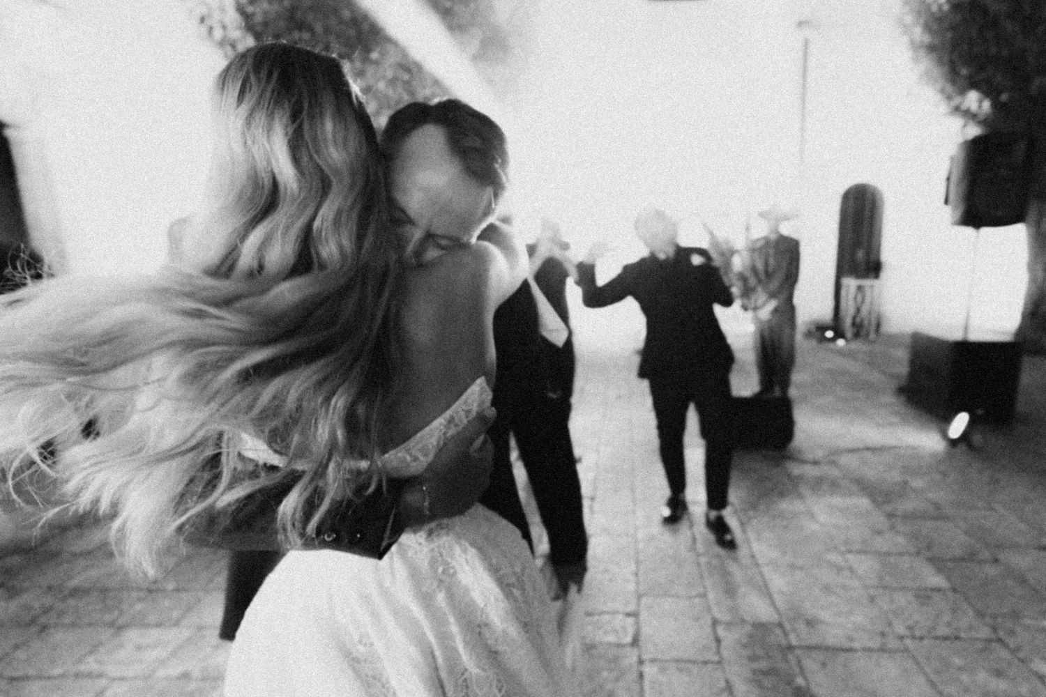 People dancing energetically at an event, with long hair flowing in motion captured in black and white photography in puglia.