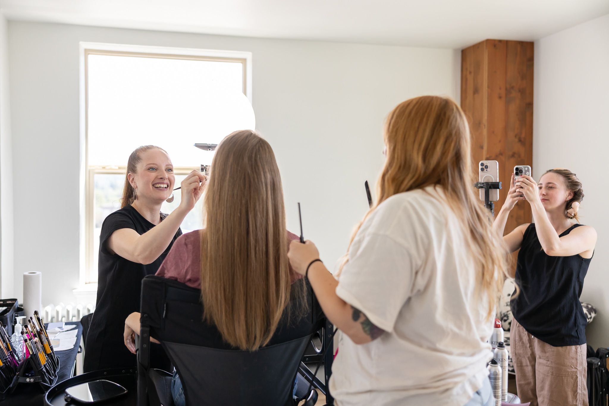 Behind the scenes of brand photoshoot in Seattle, WA team of women doing hair & makeup while other films on phone