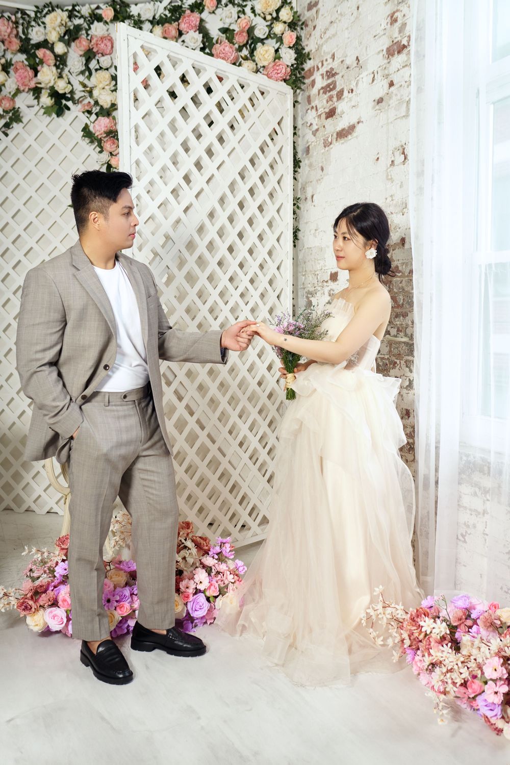 Romantic wedding scene with white lattice backdrop decorated with pink roses and floral arrangements at the base. studio photo session