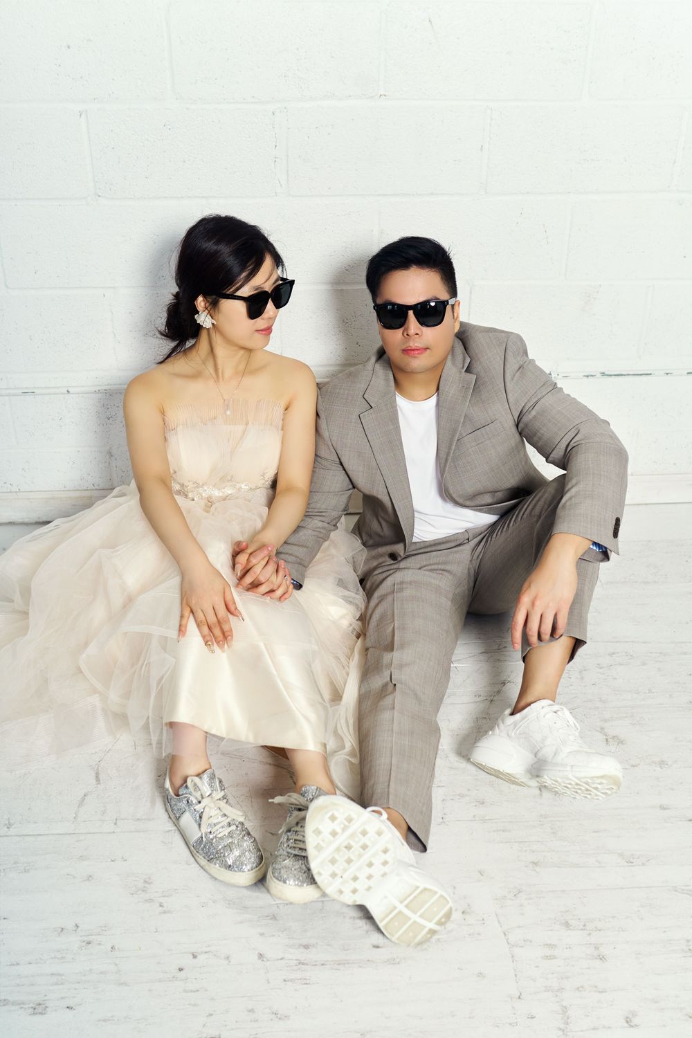 A couple in casual outfits lounge together on a white floor in a romantic style photo series. studio photo session