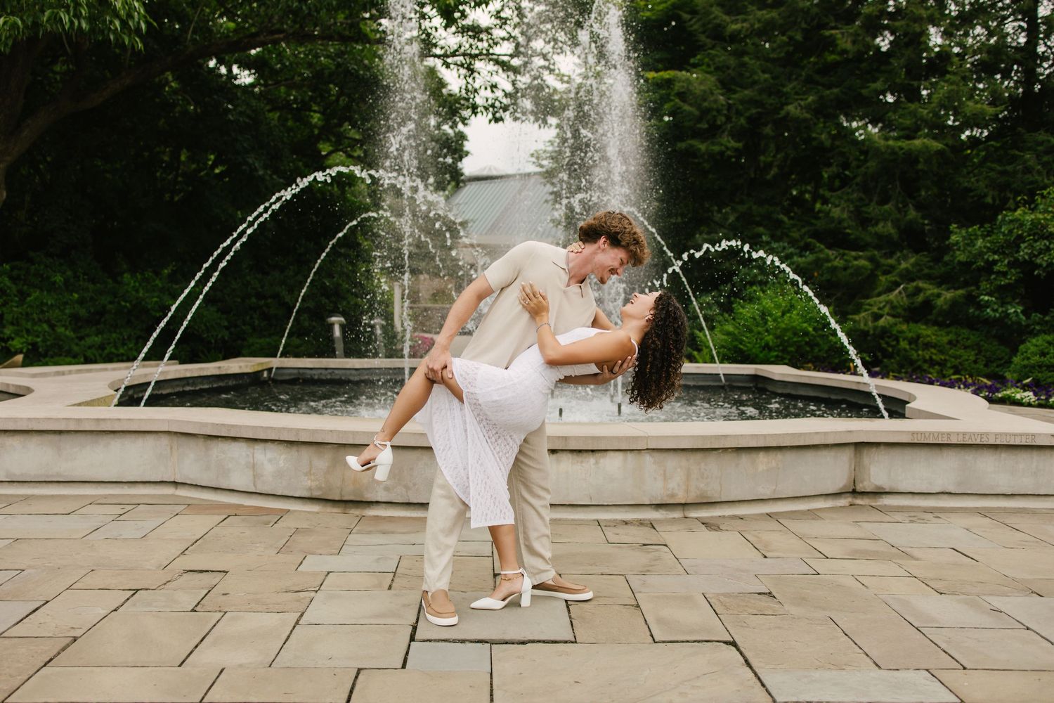 Bride's veil flows dramatically in wind during outdoor wedding portraits on golf course.