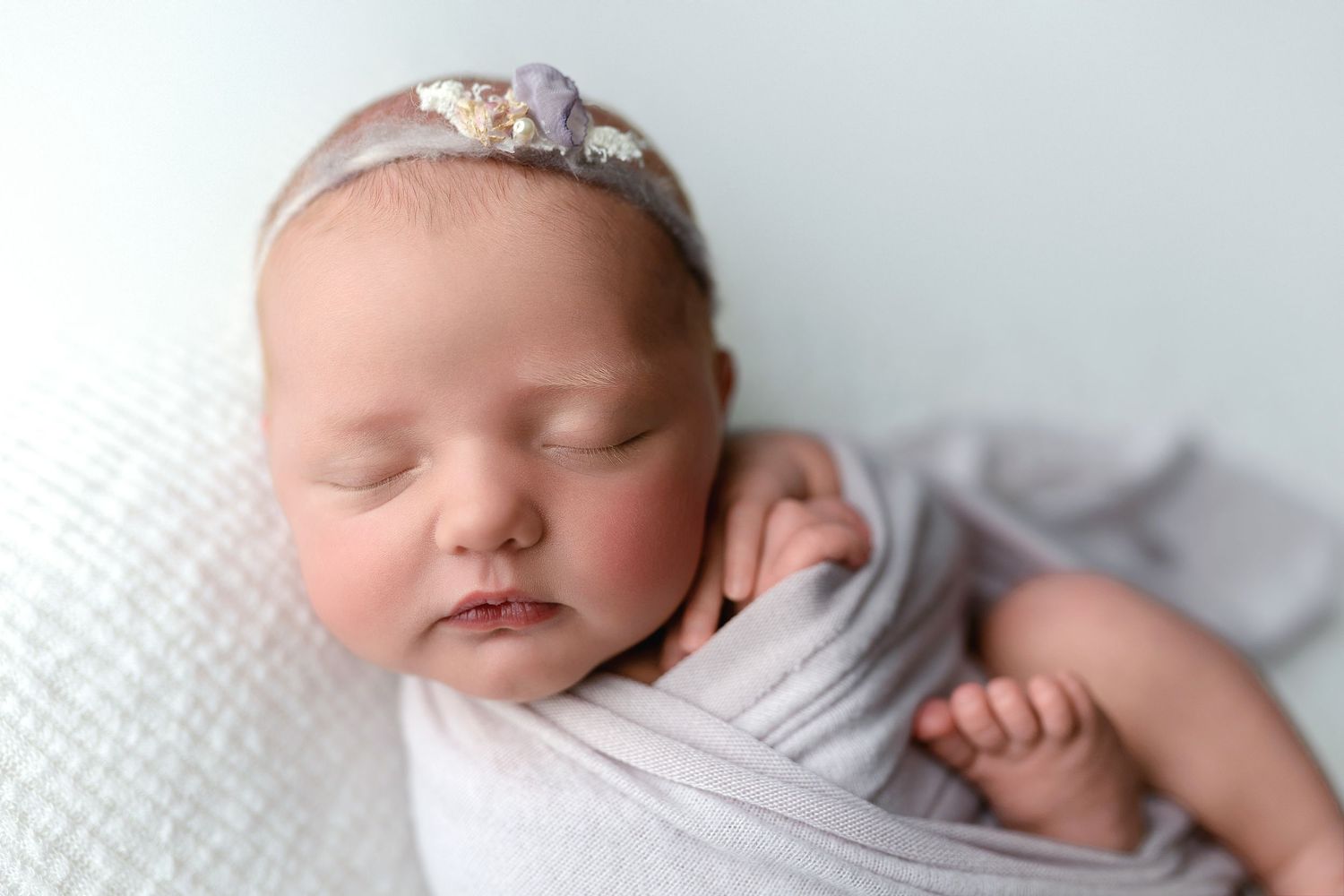 An up-close shot of a newborn girl in a light purple wrap.  - Greenville SC newborn photographer - Easley SC newborn photographer