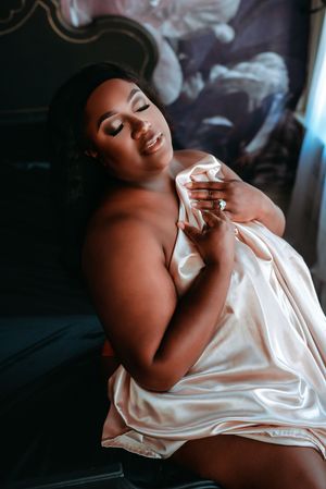 Artistic boudoir photo series showing a person draped in white silk fabric against dark background.