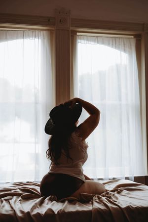 Silhouetted figures resting on bed with natural window light creating moody atmosphere.