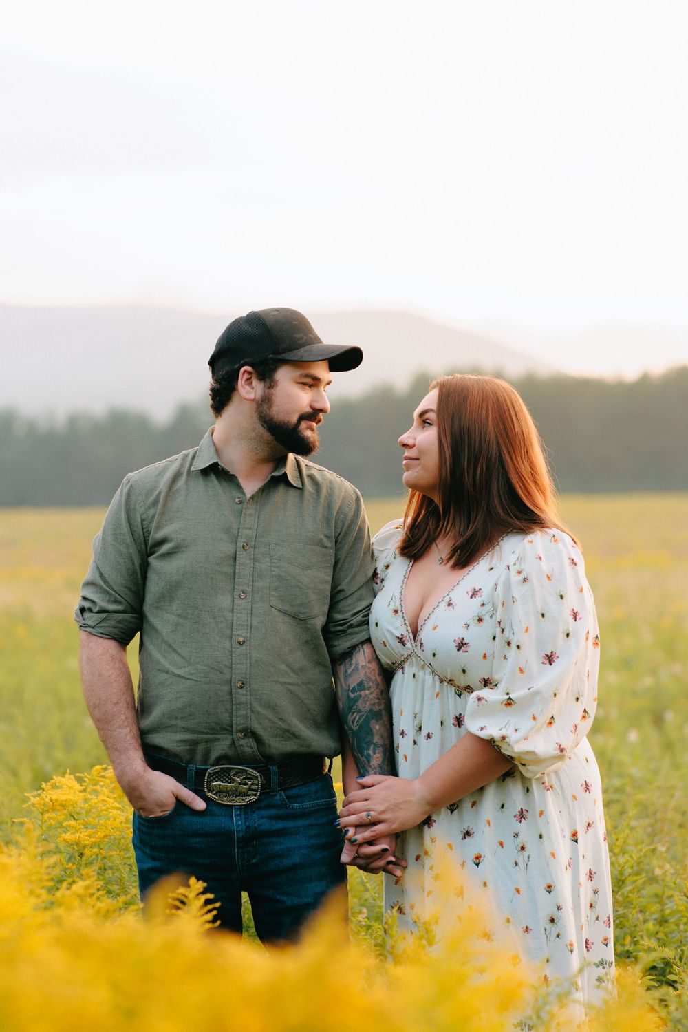A couple shares a romantic moment in a field of vibrant yellow wildflowers at sunset.