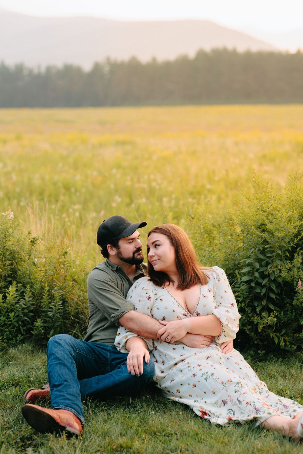 Couple relaxing together in sunlit meadow with wildflowers at sunset.