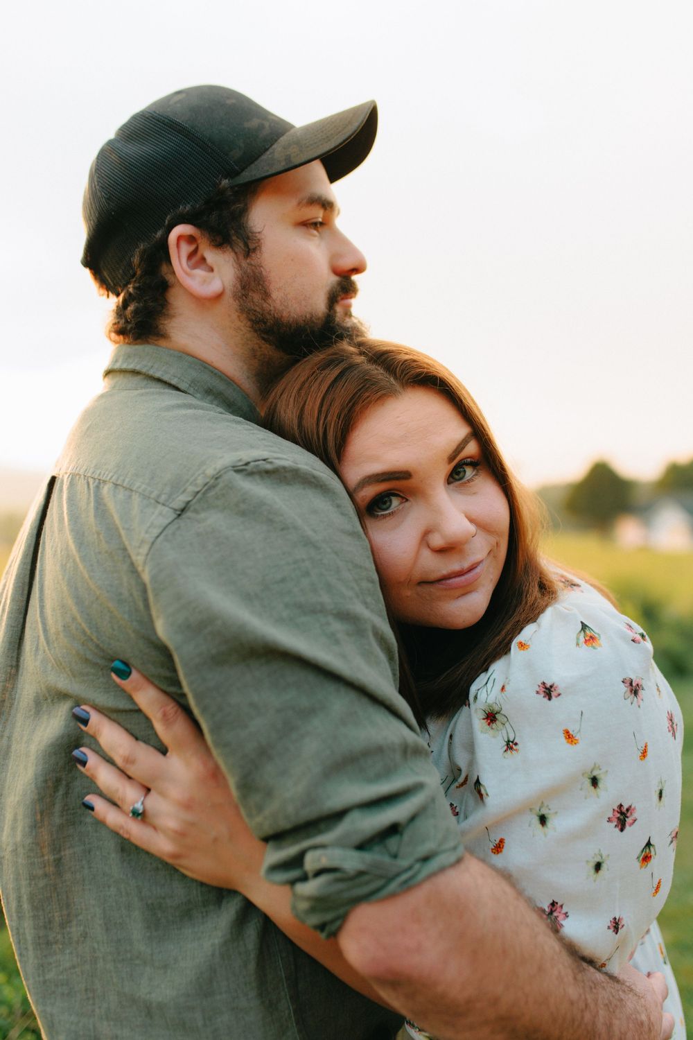 A romantic moment captured between two people hugging in a sunny field with golden light.
