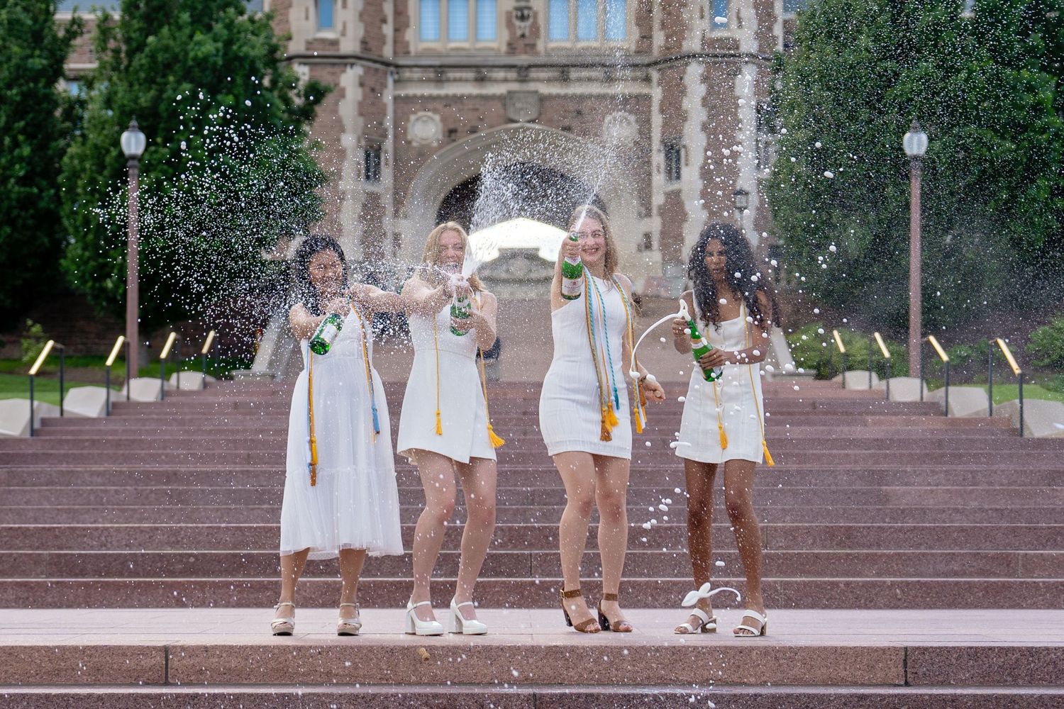 Photo of a group of girls doing a champagne pop during a cap and gown session taken by Milwaukee event photographer Rachel Dickman.
