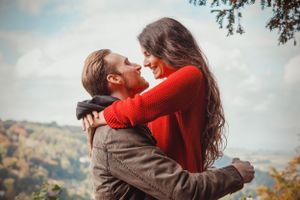 A couple embraces against an autumn mountain backdrop during a romantic photoshoot.